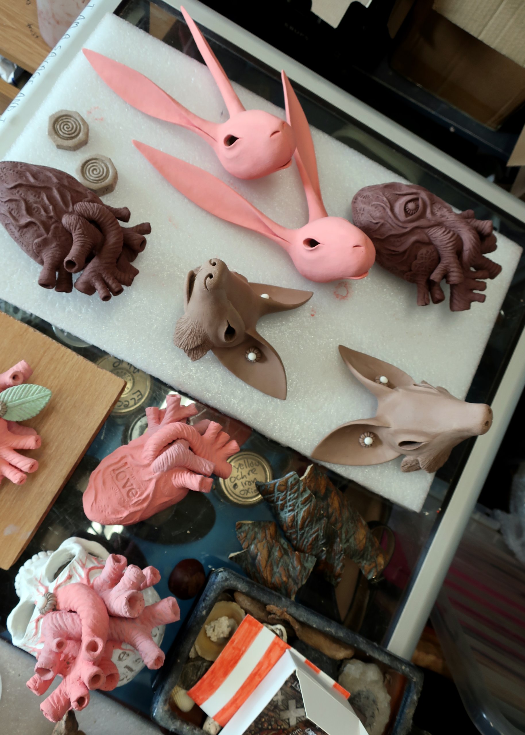 Ceramic pink hare heads, brown fox heads and ceramic hearts with flowers on by Drew Caines, placed on a trolly.