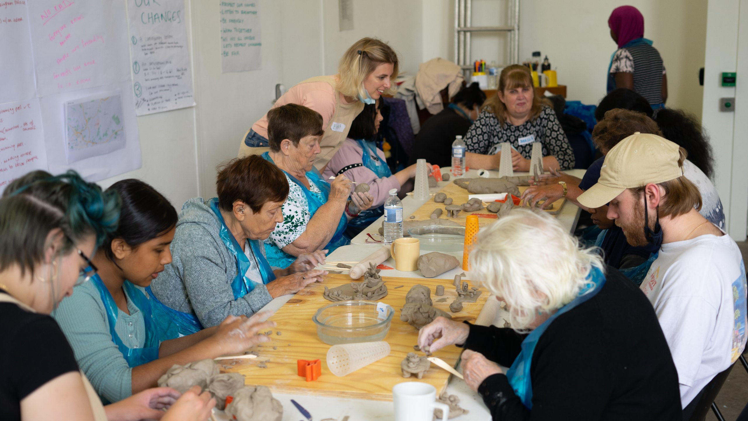 Burmantofts Senior Action residents are sat around a table mingled with the young people. They are sculpting things they would add to their neighbourhood with clay.